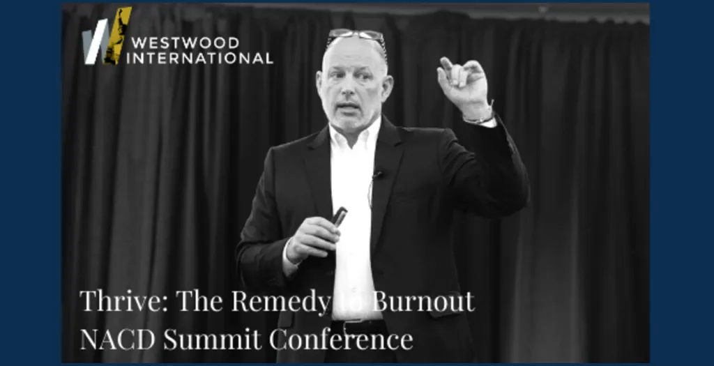 Greg Zlevor speaking on stage at the NACD Summit Conference with the Westwood International logo above.
