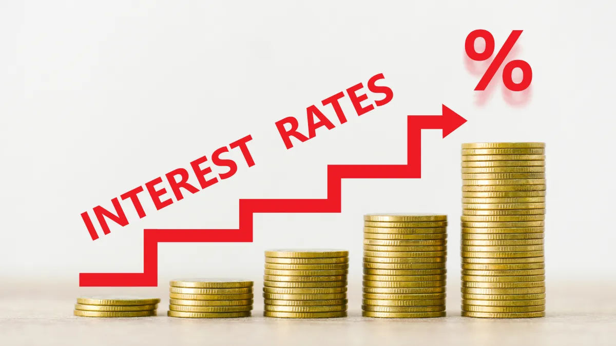 Stacked gold coins with a red upward arrow labeled “Interest Rates,” representing rising borrowing costs and increasing credit card debt in 2025.