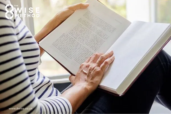 Side on view of a person sat in a window sill reading a book
