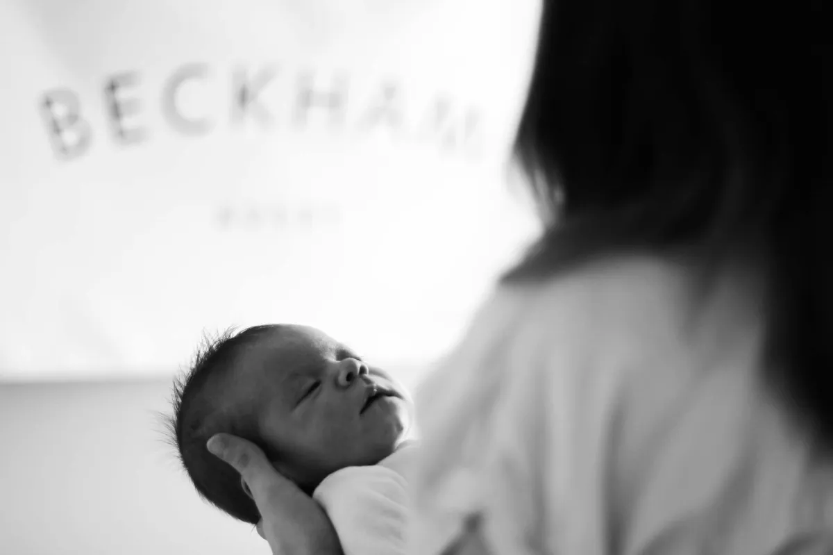 Black and white photo of a mother holding a sleeping newborn in here arms