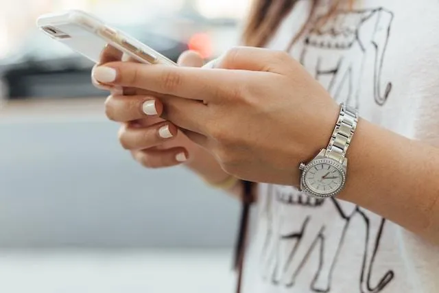 Women scrolling on a cellphone outside.