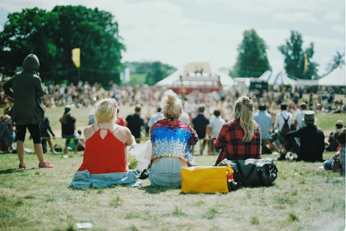 A group of people on sitting on the Green Grass in the Field.