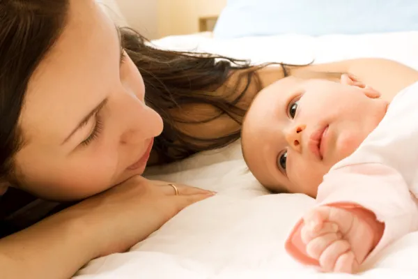 Mum observing her baby during early feeding days, representing breastfeeding pain patterns where nipples stay sore even when latch appears fine.