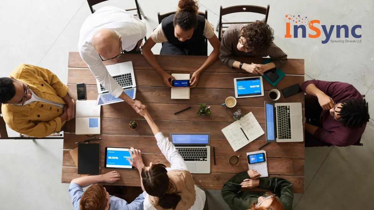 Diverse group of professionals collaborating around a table in a modern, bright office, symbolizing teamwork and a positive workplace culture.