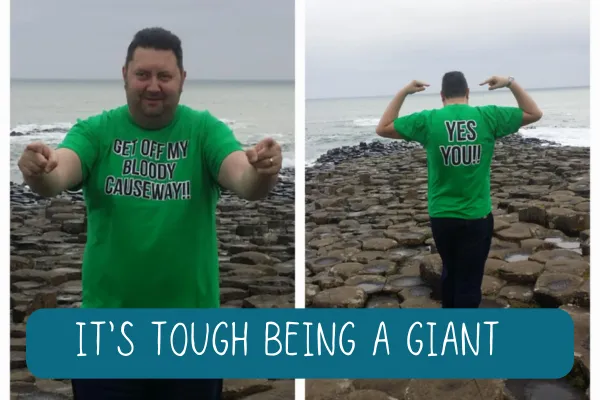 Man in green t-shirt which says 'get off my causeway' standing on the giants Causeway in Ireland