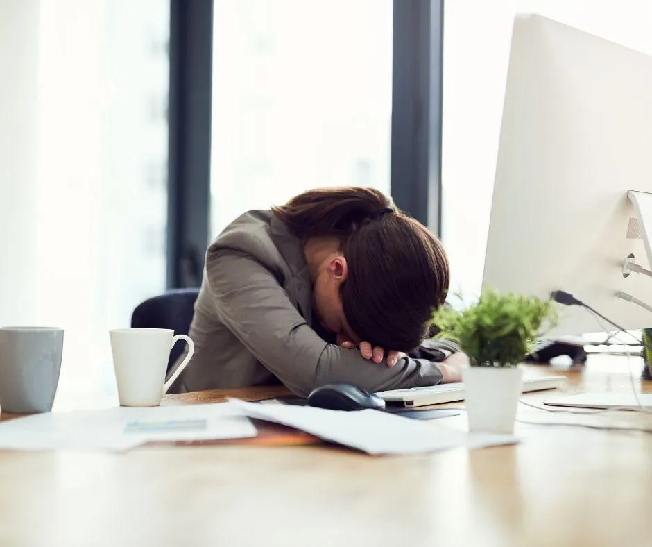 Burned out accountant overwhelmed at desk during tax season, showing work-life imbalance in the accounting profession.