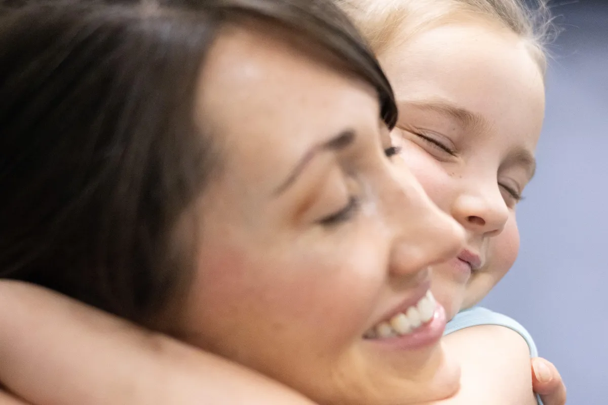 A young dancer and her mother share a warm embrace after the girl's dance class.