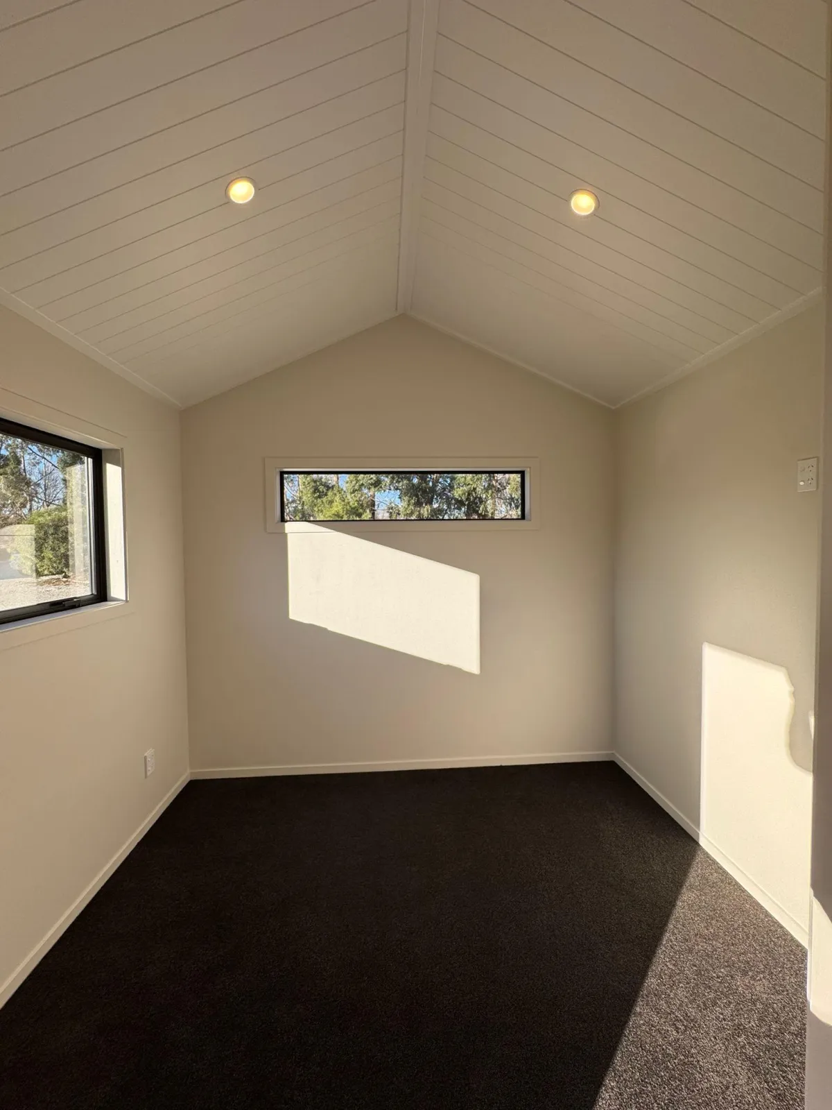 Carpeted room with large double-glazed windows and vaulted ceiling in portable cabin.