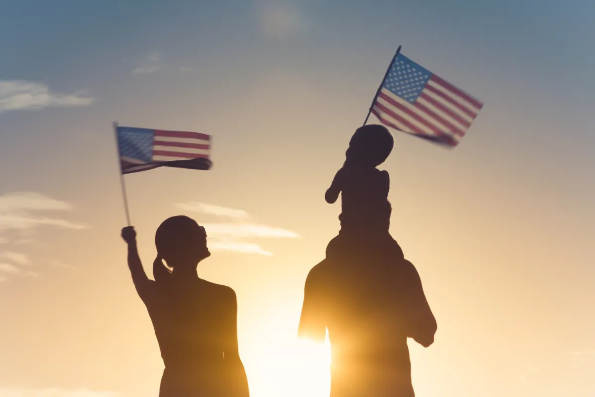 A mother and father wave American flags with their child