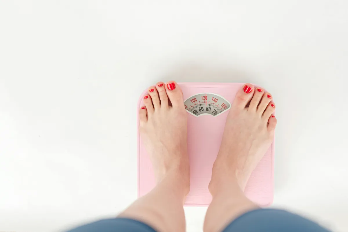 A close-up of a scale on a tile floor, symbolizing weight management and health.
