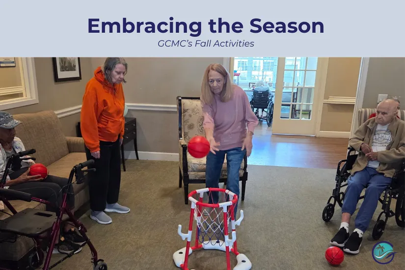 Residents at Gulf Coast Memory Care enjoying fall activities with adaptive basketball game in the community living room, featuring seniors participating in seated sports and movement activities