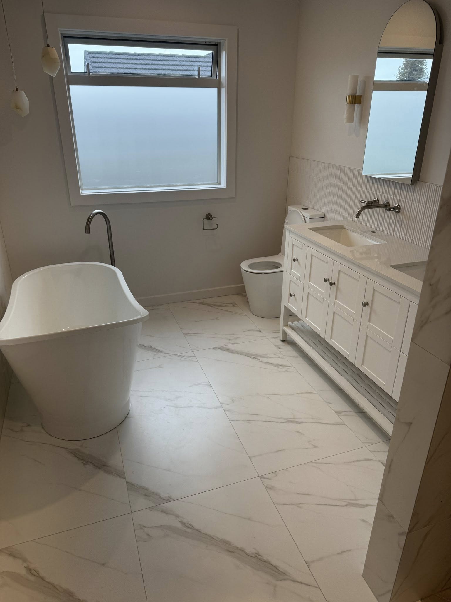 Full bathroom renovation with freestanding bath white cabinetry and large format floor tiles by Remarkable Contracting in Hawke's Bay