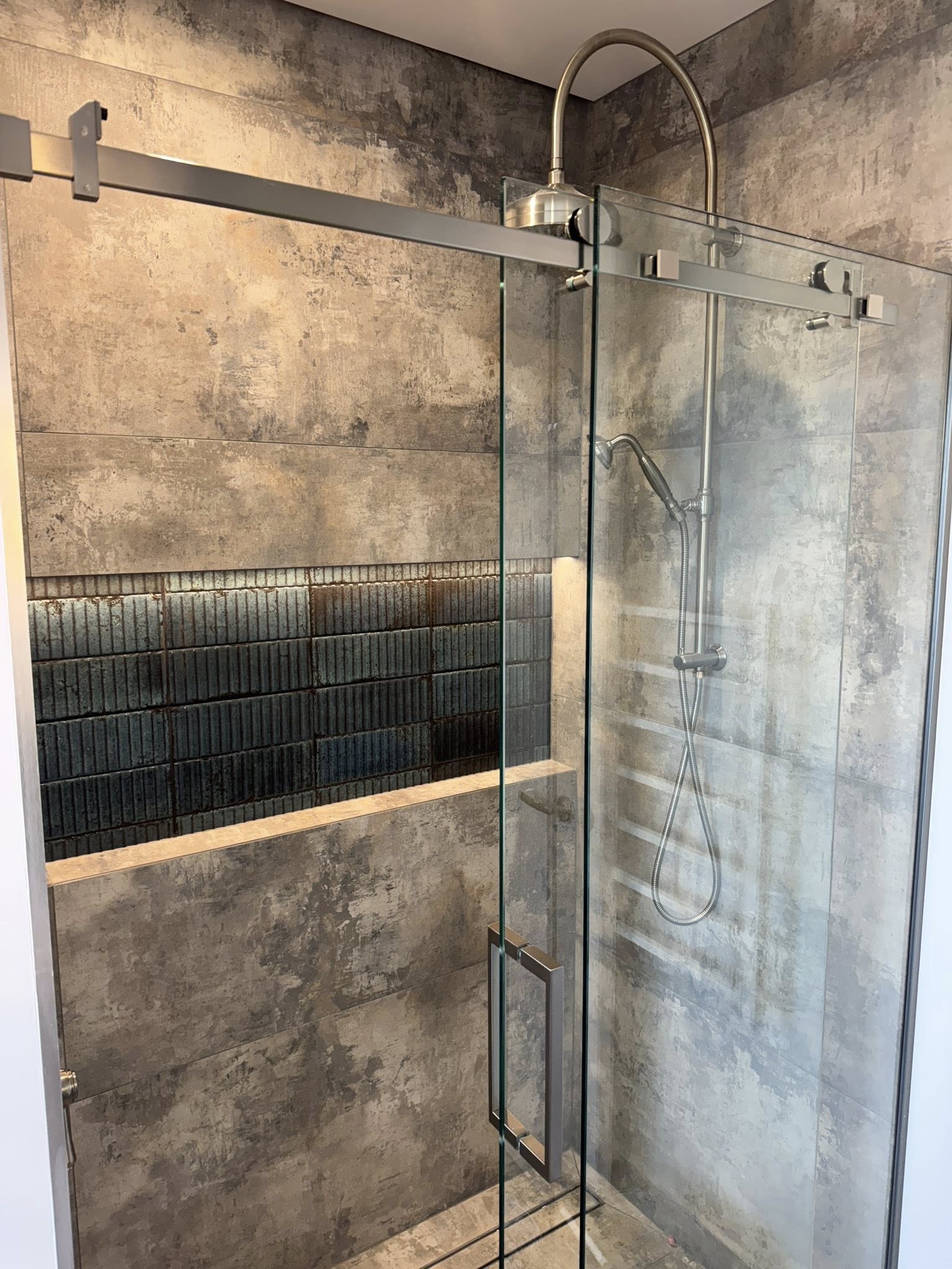 Industrial style tiled shower with dark feature tiles and frameless glass screen completed by Remarkable Contracting in Napier