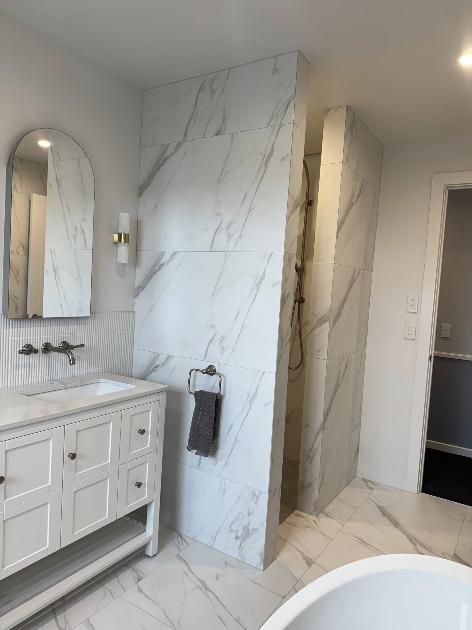 Marble look tiled bathroom with freestanding bath vanity and chrome fixtures by Remarkable Contracting in Napier