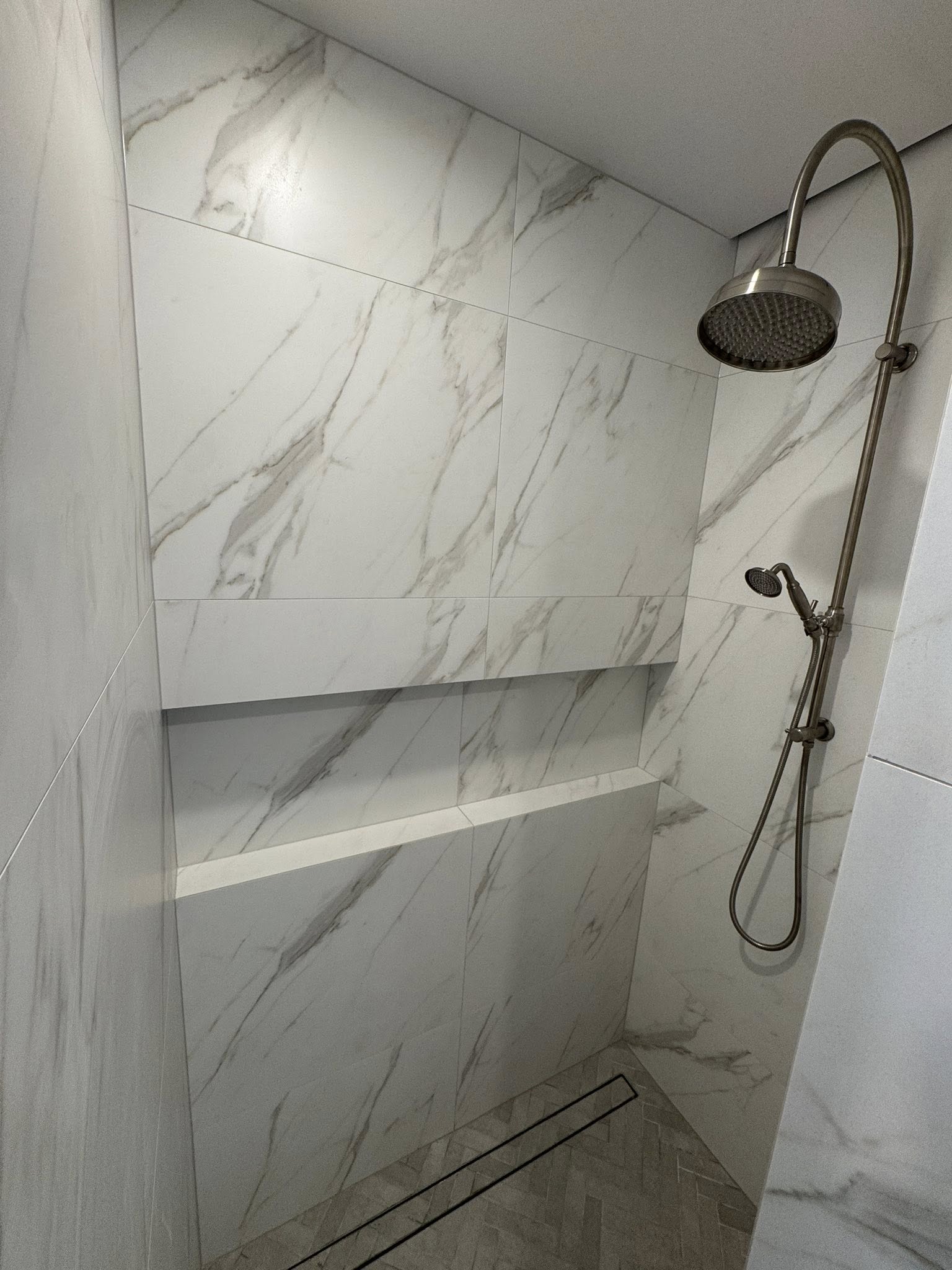 White marble look wall tiling with built in shower shelf and chrome fittings installed by Remarkable Contracting in Hawke's Bay