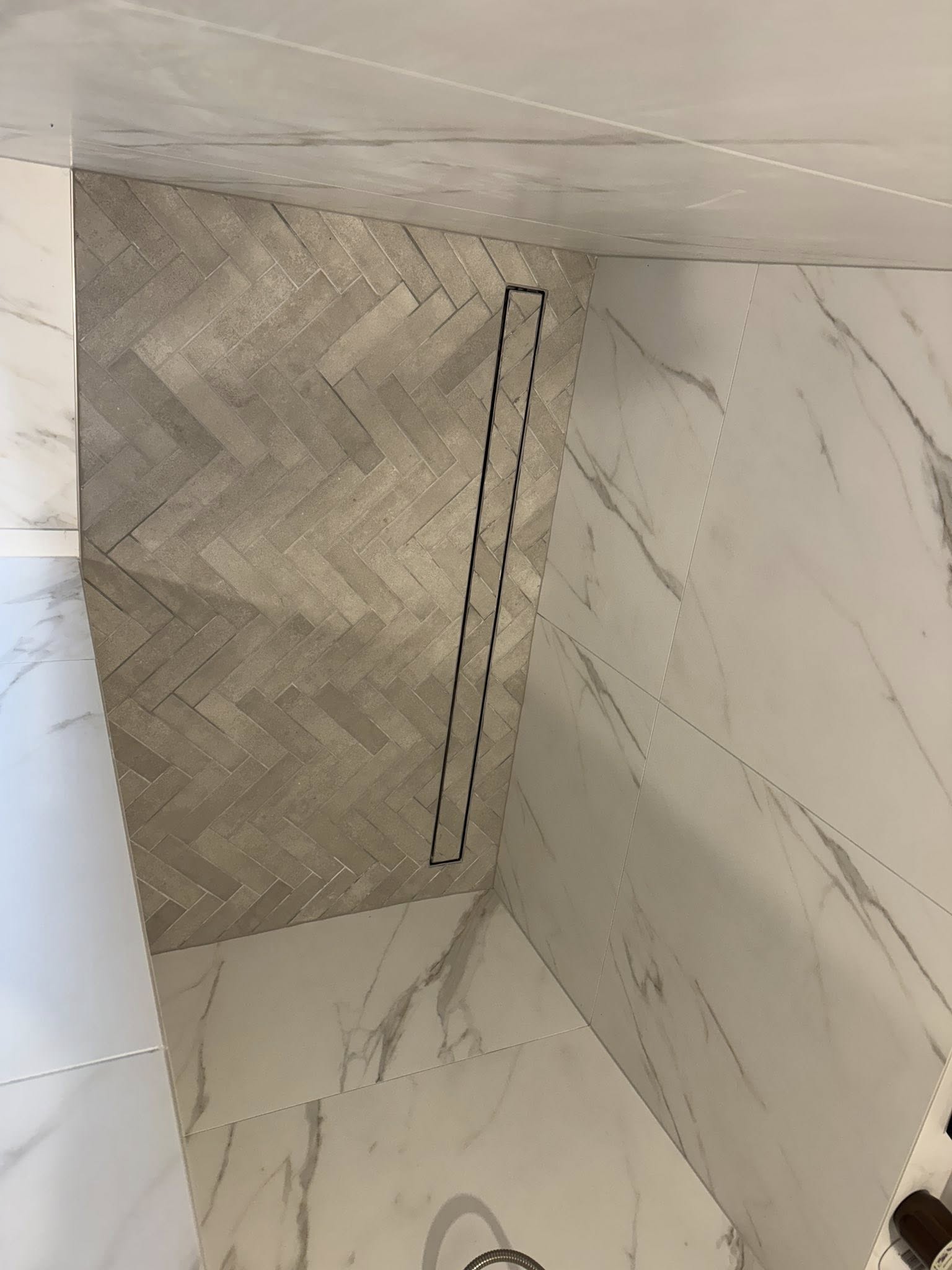 Herringbone pattern wall tiling in a modern shower with linear drain installed by Remarkable Contracting in Napier