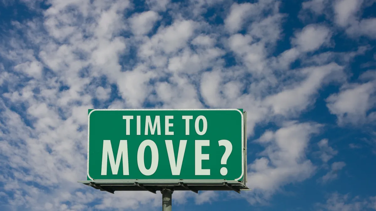 A green highway-style sign with white letters reading “TIME TO MOVE?” set against a bright blue sky with scattered clouds, symbolizing relocation, change, or a new beginning.