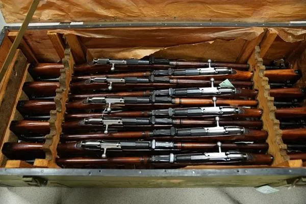 A collection of historic Soviet M91/30 Mosin-Nagant bolt-action rifles neatly arranged in their original wooden military crate.
