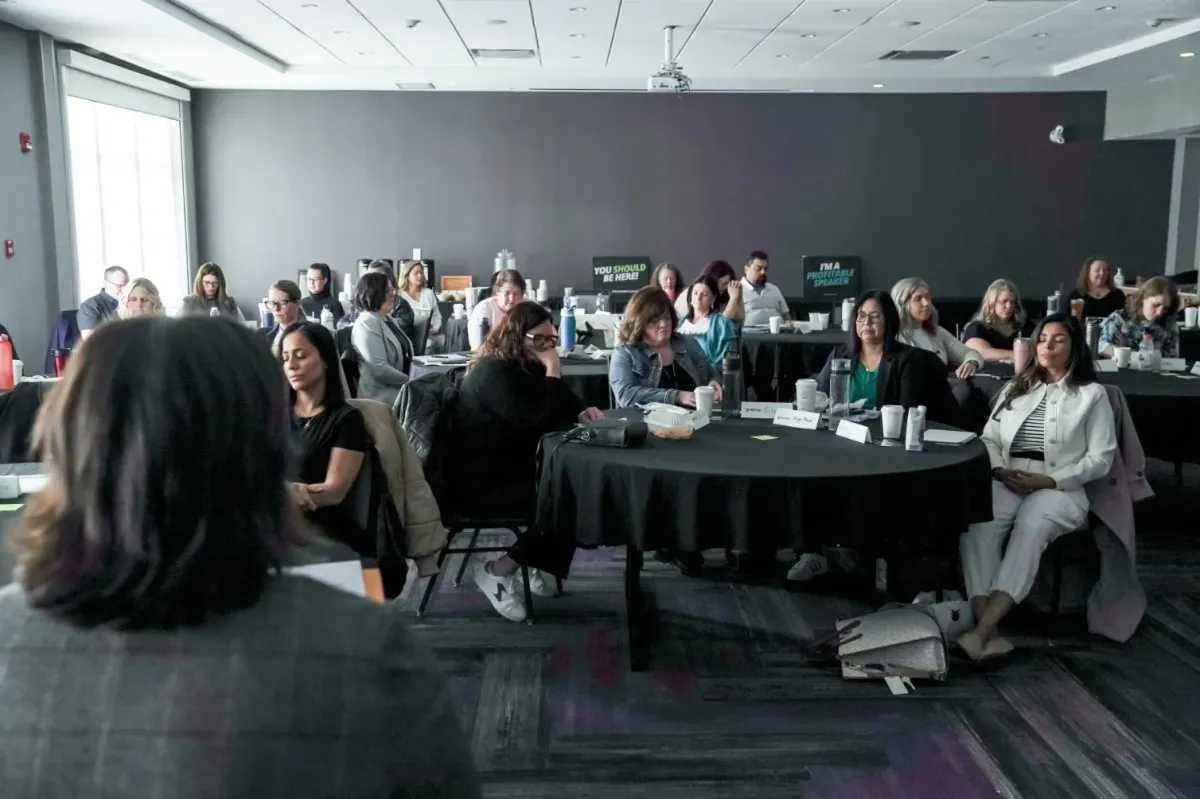 Bootcamp attendees seated with eyes closed during a guided visualization session in a dimly lit room.