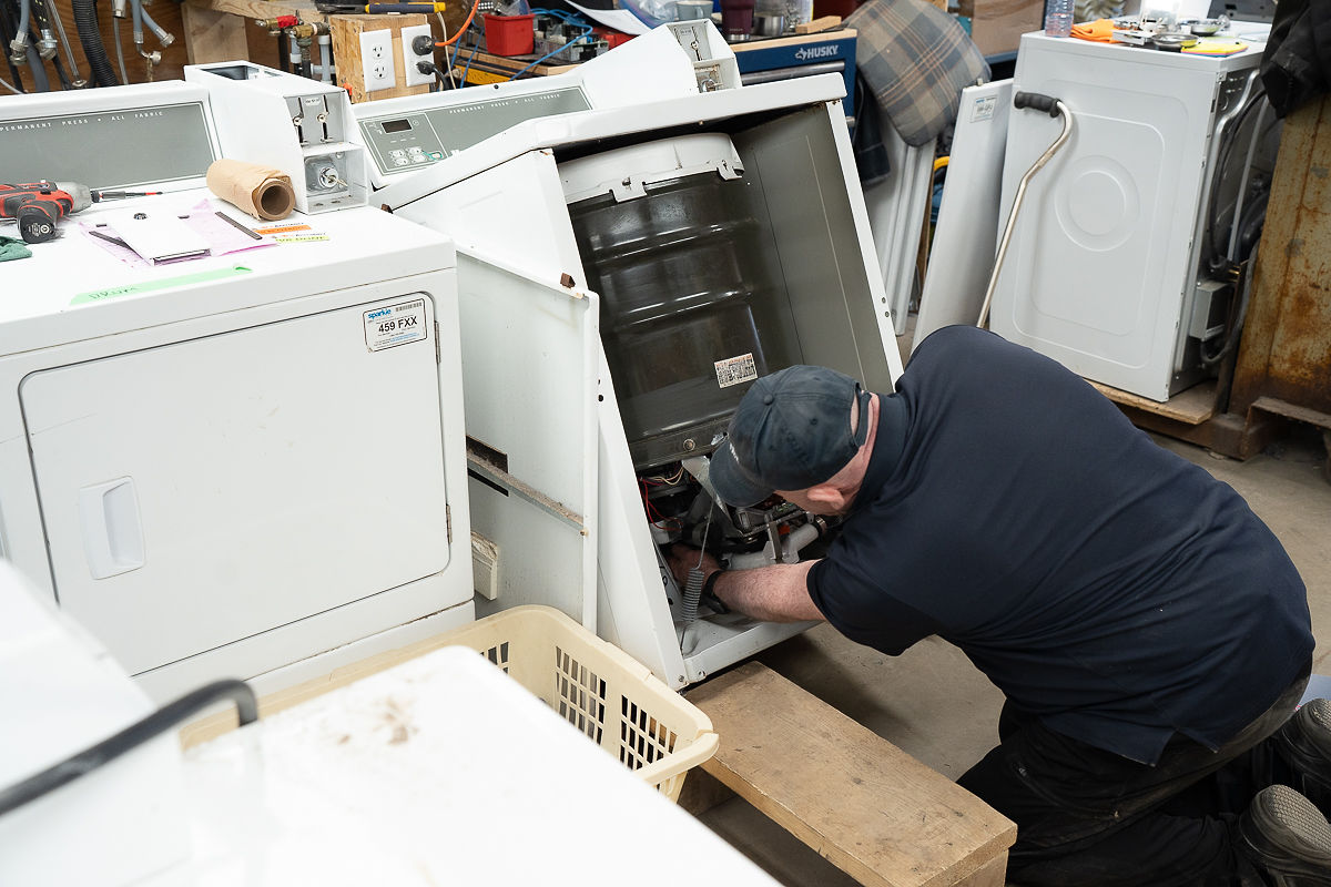 Repairman fixing a coin-operated washing machine.