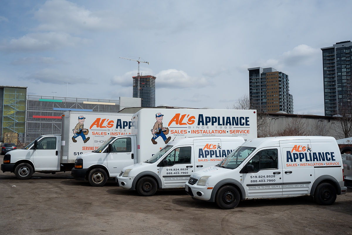 4 different Al's Appliance delivery and maintenance call trucks and vans parked next to each other cascading from biggest to smallest.