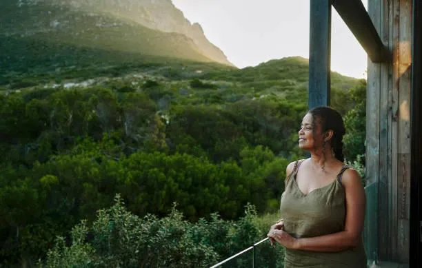 A serene woman standing in a peaceful setting, her arms open, symbolizing release and emotional freedom.