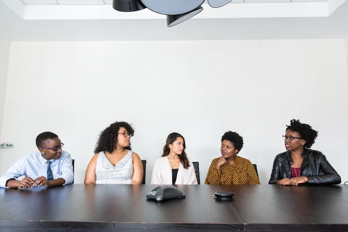 A diverse team in a calm office environment practicing empathetic leadership and emotional safety, with teal green accents throughout.