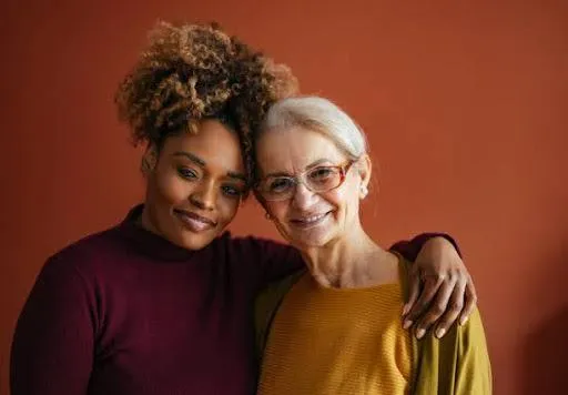A senior woman and her caregiver share a warm embrace, reflecting trust, empathy, and happiness in a supportive environment- Stock photo.