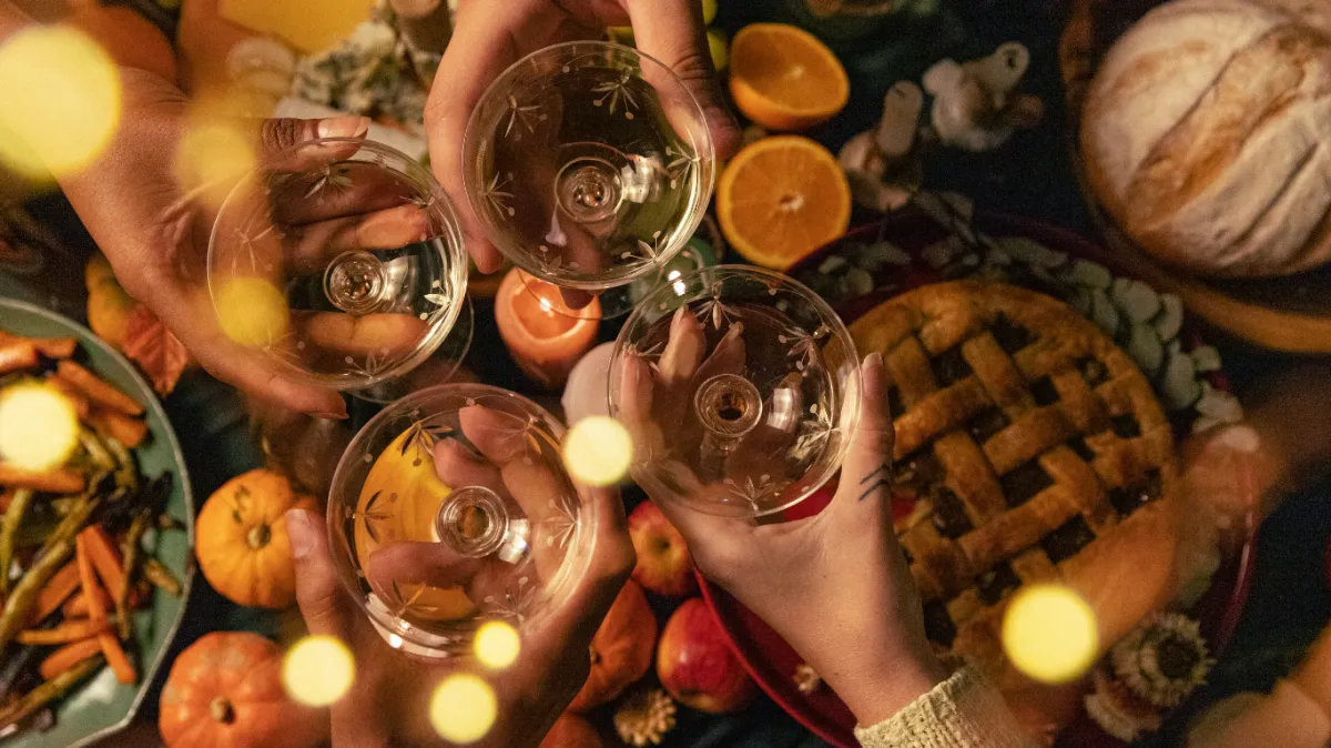 Four people toasting with wine over a Thanksgiving table filled with seasonal foods like pie, roasted vegetables, pumpkins, and candles—capturing the warmth, connection, and wellness of a meaningful holiday celebration."