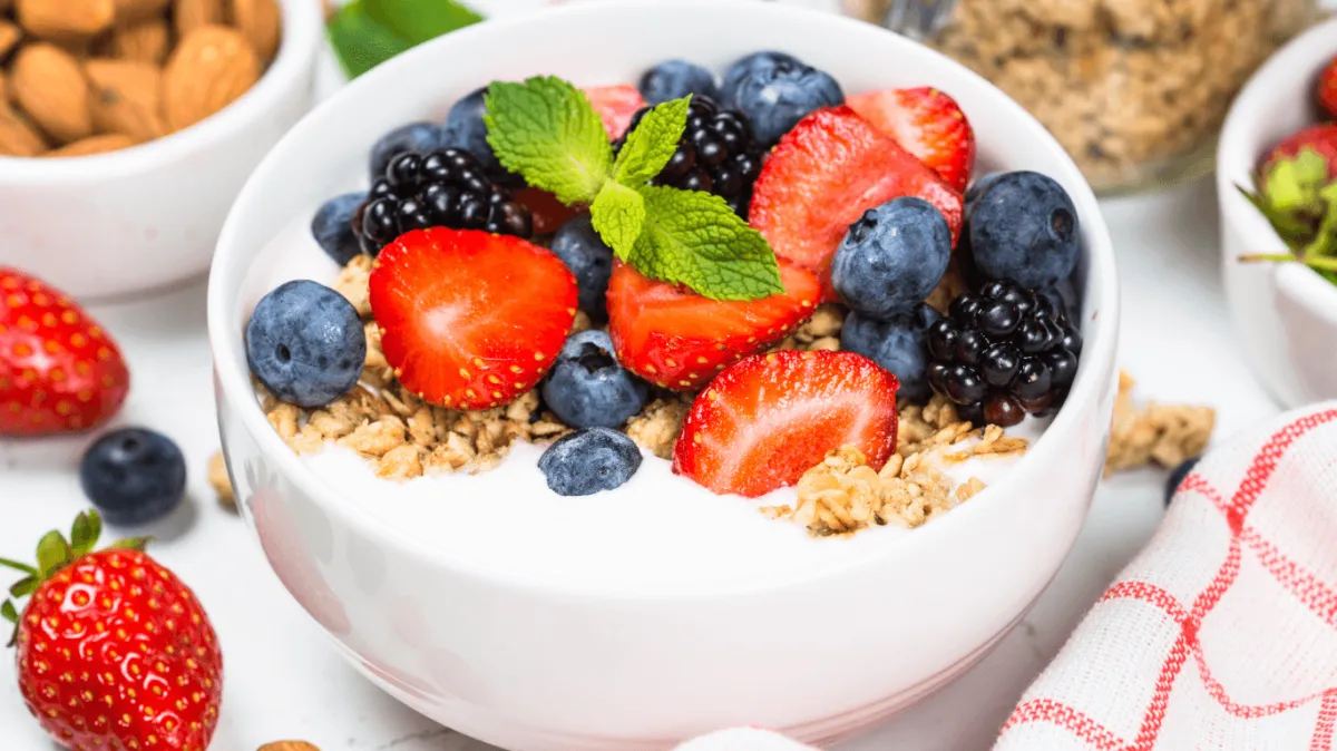 How to Reduce Sugar Cravings: a wholesome bowl of yogurt with granola, berries, and almonds as a nutritious alternative to sugary snacks.
