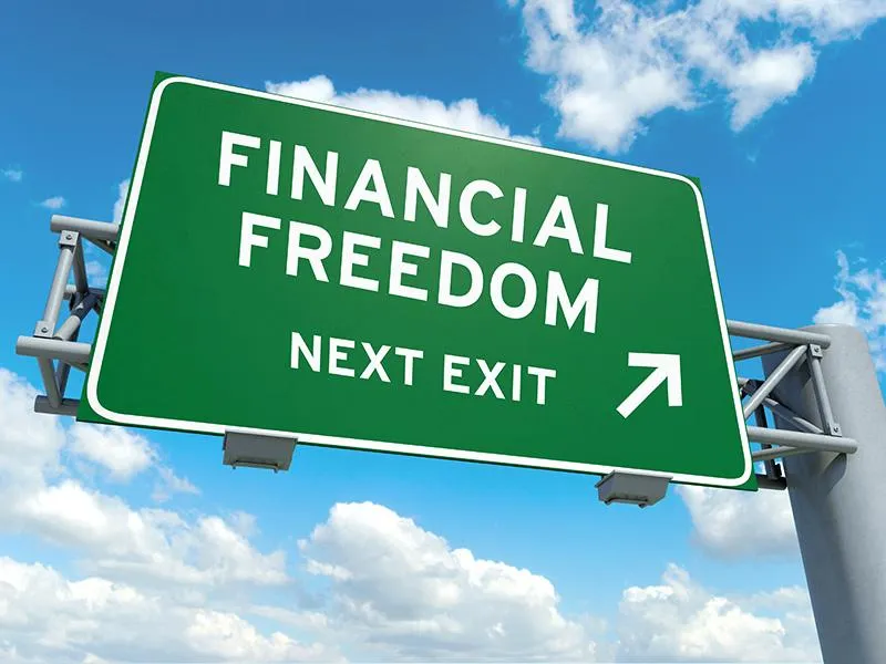 A green highway sign reads "FINANCIAL FREEDOM NEXT EXIT" with an arrow pointing to the right.