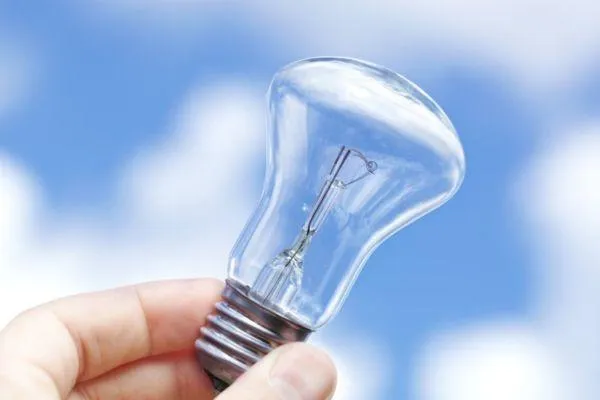 light bulb being held against a blue sky