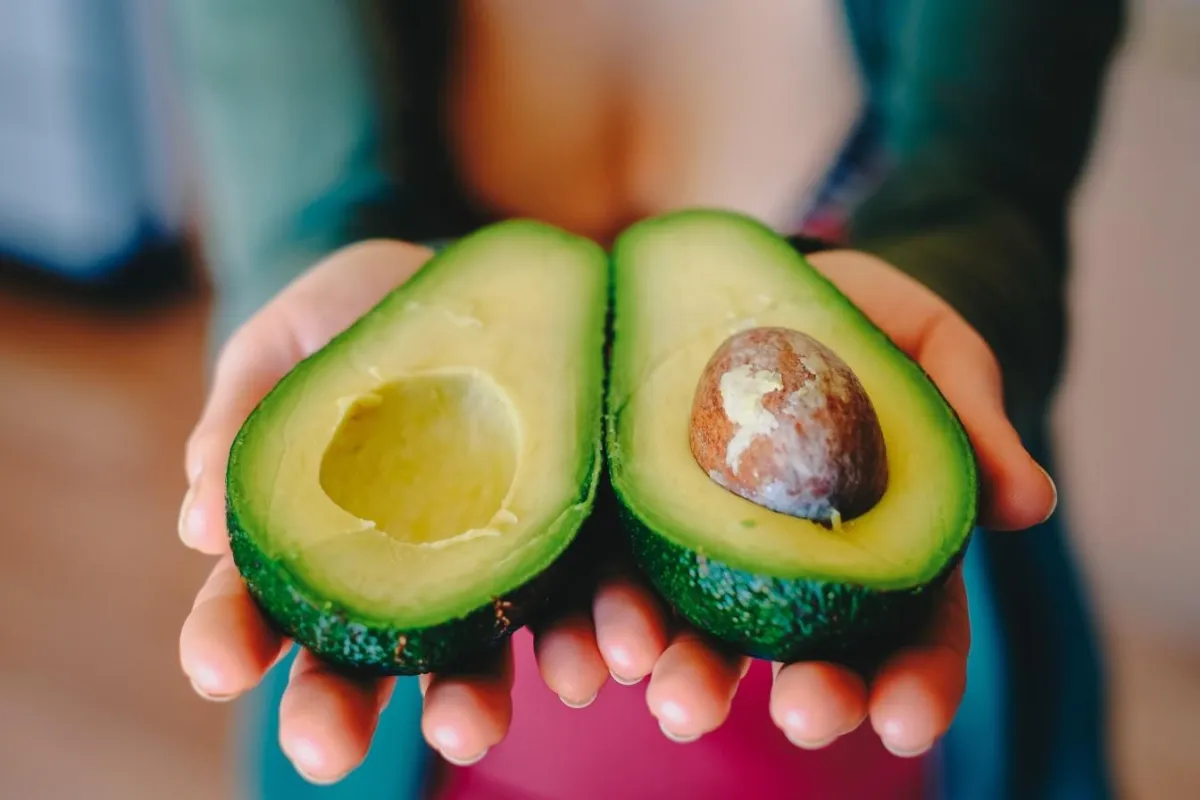 hands holding two avocado halves