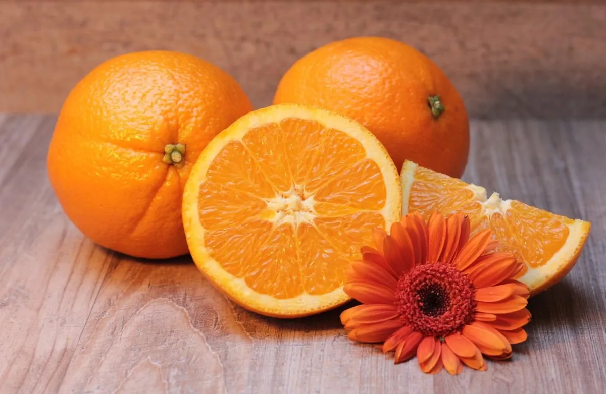 oranges, whole and halved, on a wooden board