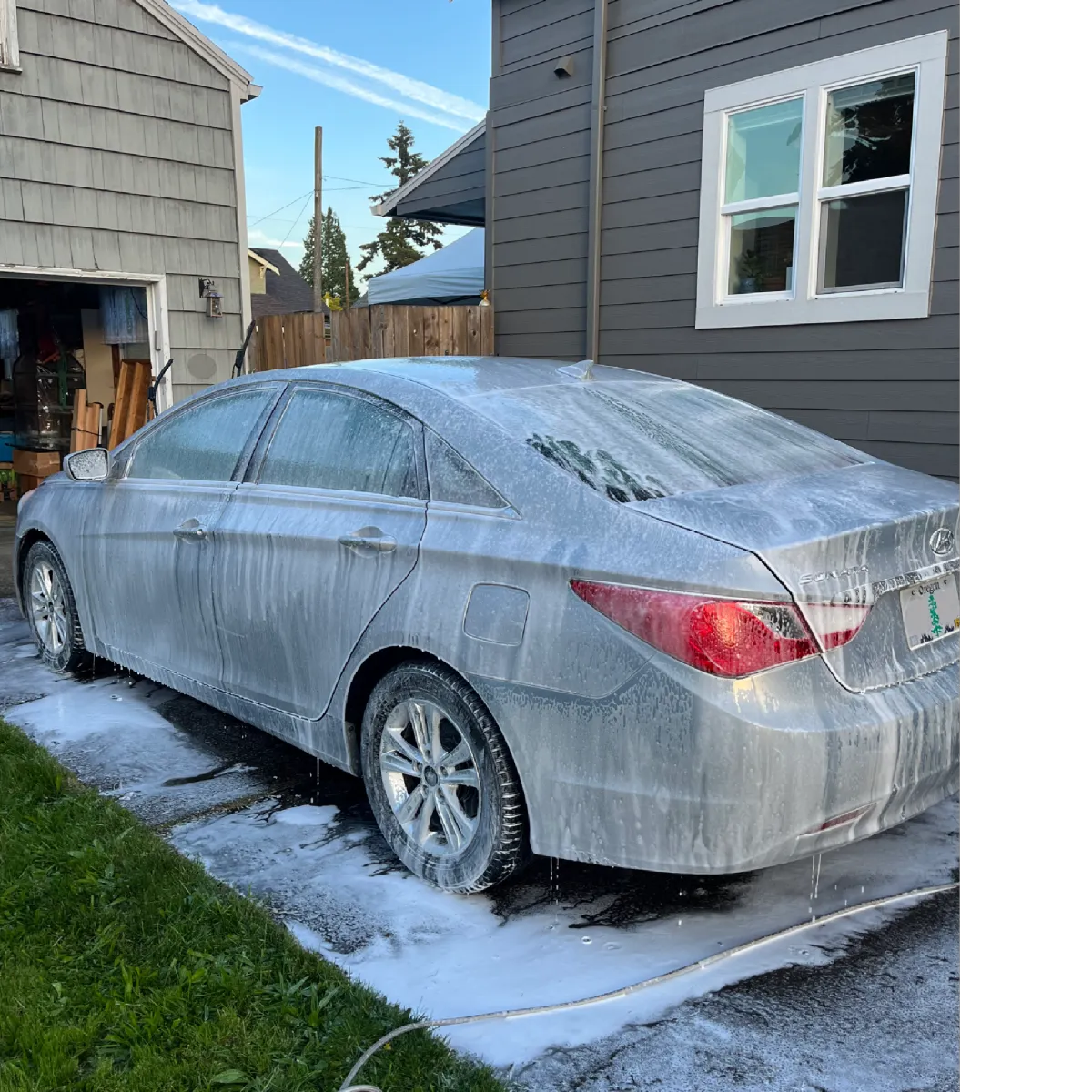 Silver compact car covered in foam during detail