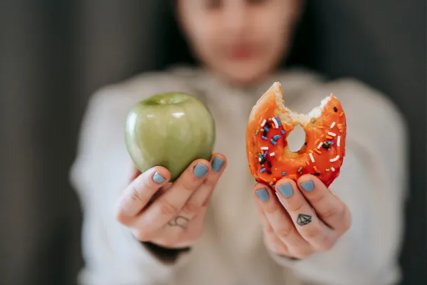 Woman holding a donut and an apple