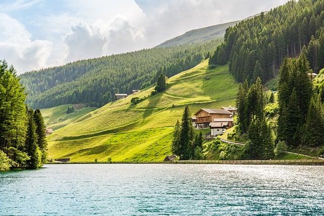green hills surrounding a lake with a small house