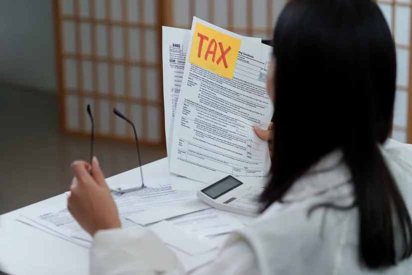 Tax review. Woman examining tax documents and preparing for filing Photo by Canva