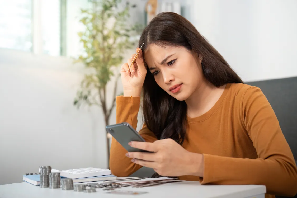 Financial Stress. Woman worried about personal finances while using smartphone. Photo by Canva