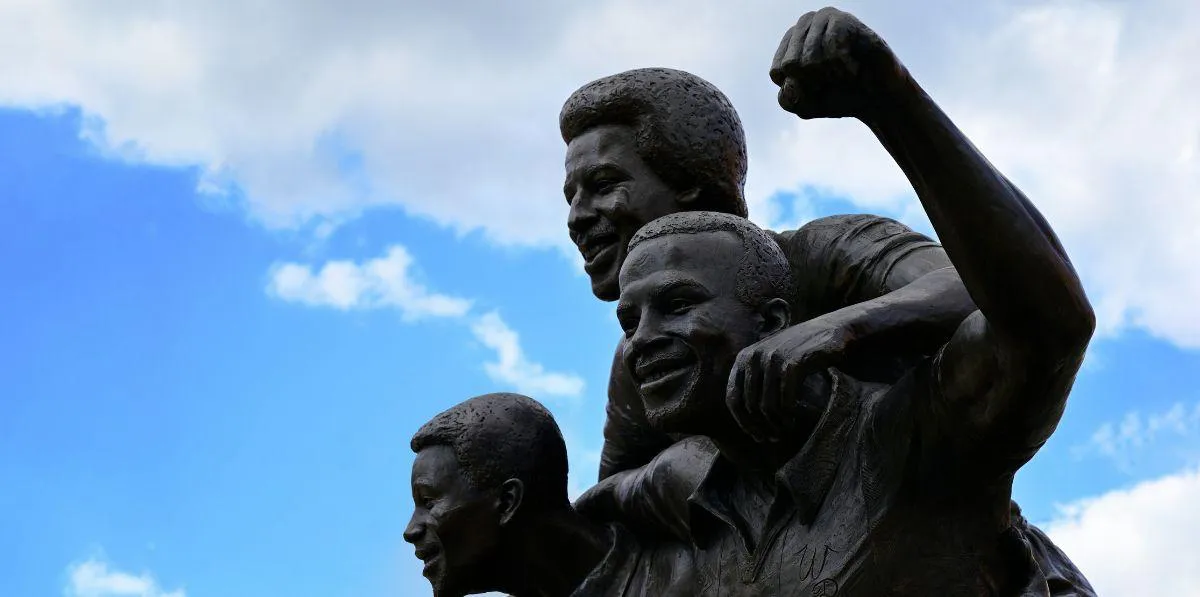 Bronze statue of three smiling figures celebrating together.