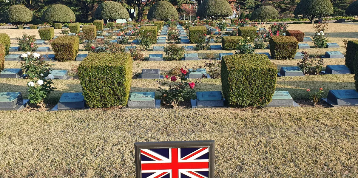 Cemetery with trimmed bushes and British flag