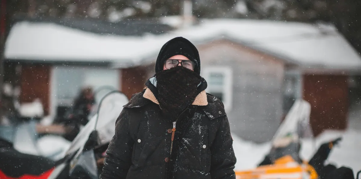 Bundled person standing in falling snow.
