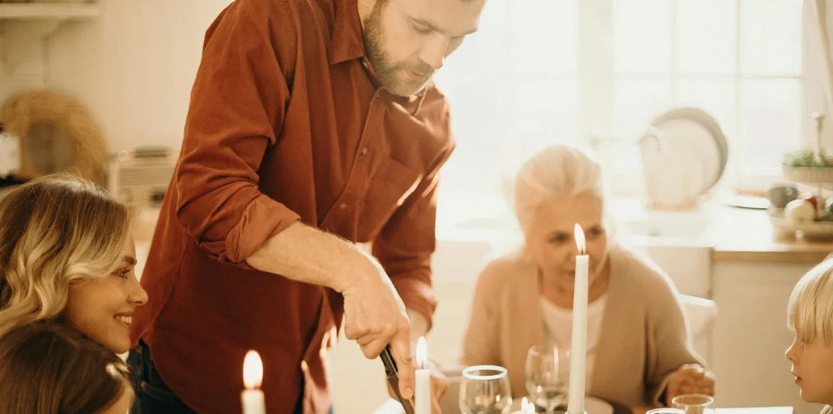 Man serving food at a family table.