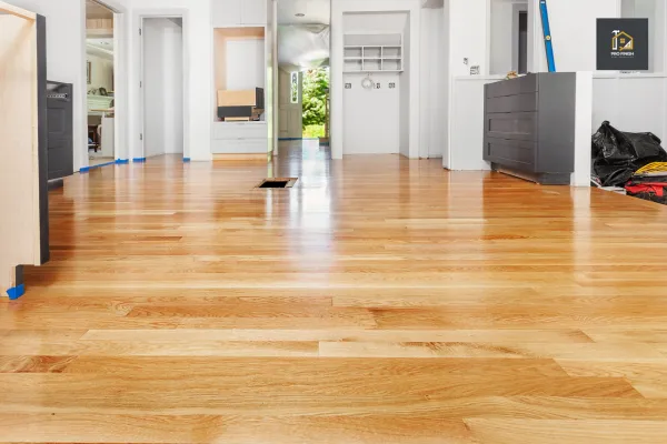 A beautifully installed hardwood floor in a modern home with natural light reflecting off its smooth finish. The room is in the process of renovation, with cabinets and fixtures partially installed.