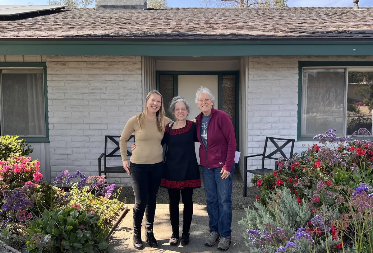 Three people standing in front of a house