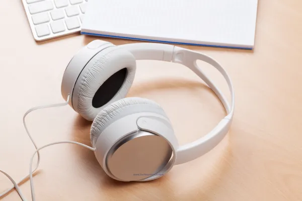 How to launch a podcast for beginners in 7 simple steps and at bottom of graphic it shows a notebook and a pair of headphones