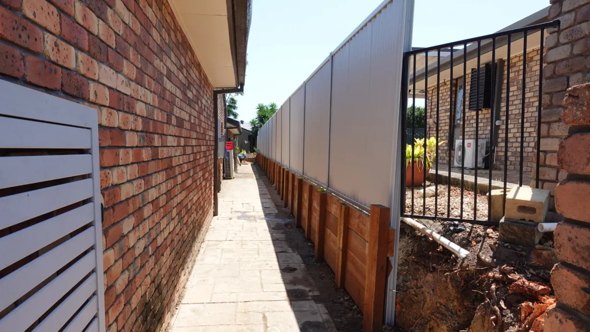 Sleeper retaining wall with treated pine sleepers and construction tools.