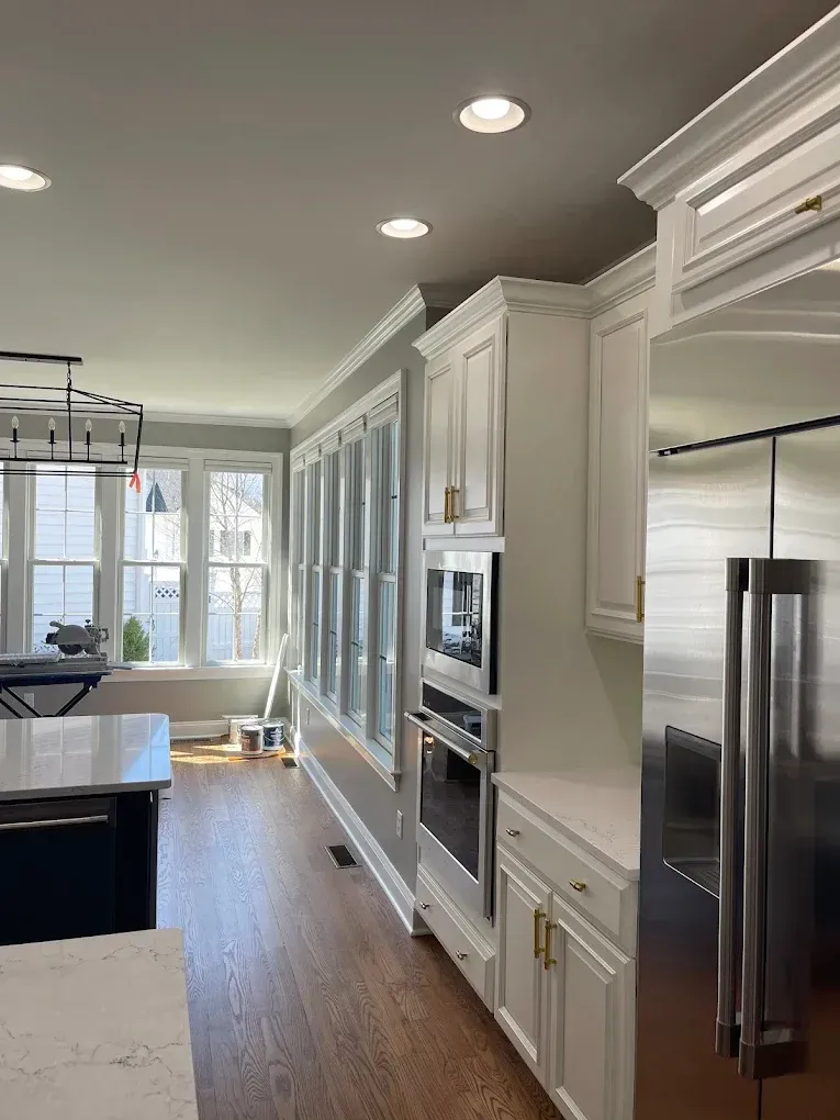 Modern kitchen interior featuring white cabinetry, stainless steel appliances, and hardwood flooring, showcasing a bright and inviting space ideal for residential painting projects in Easton, MD.