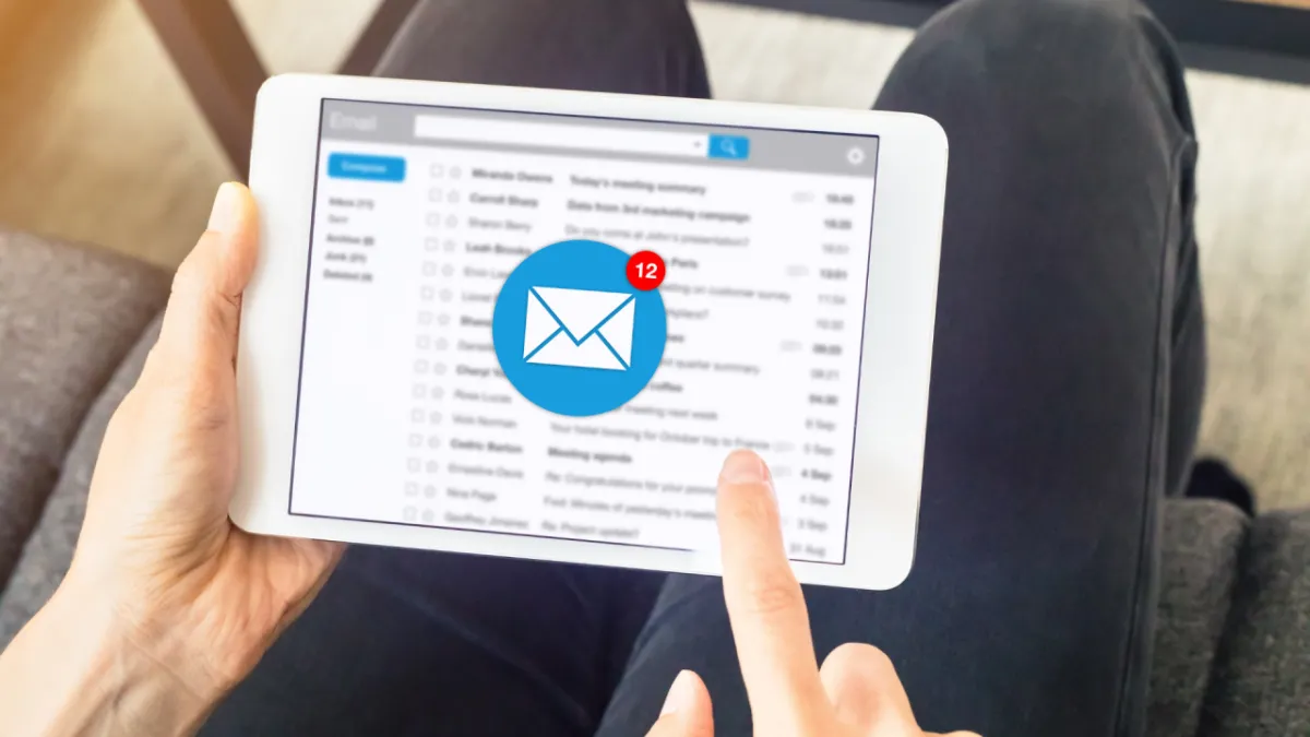 a person holding a tablet with an email inbox open about to open an email, representing engagement on a cold email campaign.