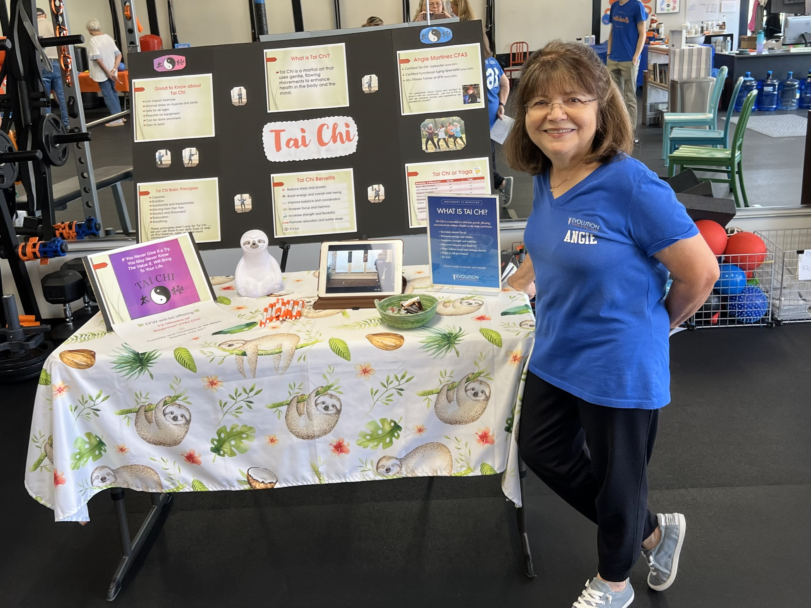 Angie standing in front of a table with tai chi information